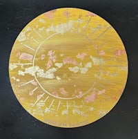 a yellow and gold plate with a sun on it